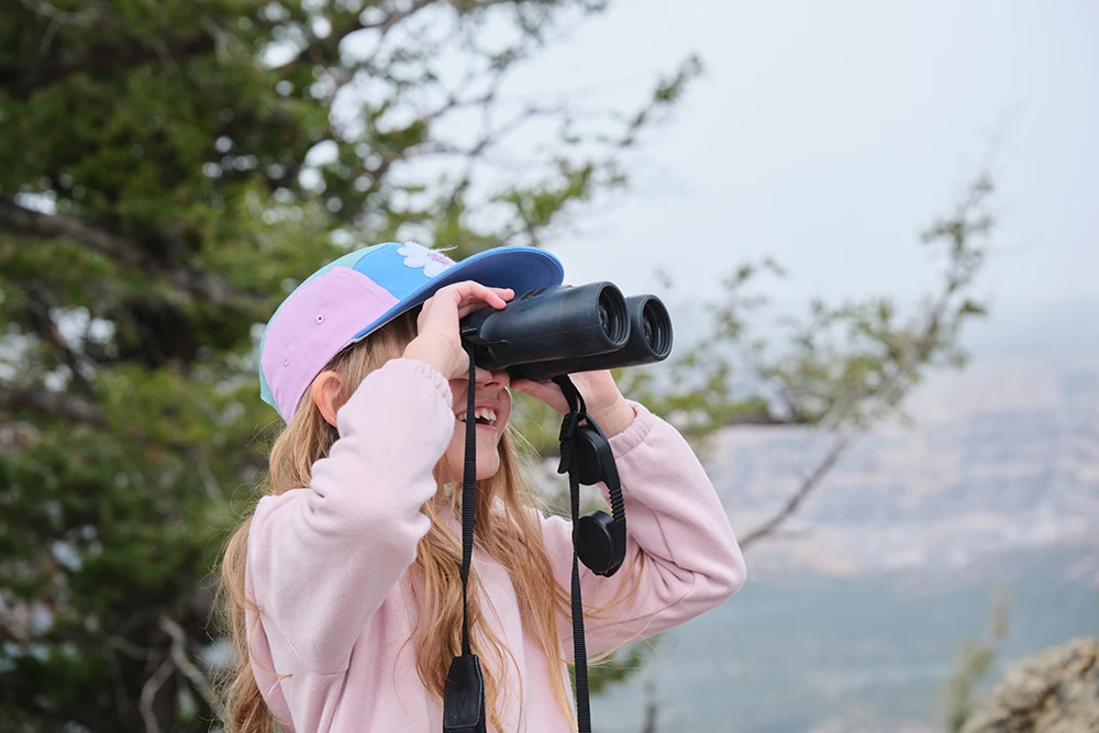 Child using binoculars with canyon backdrop at Dinosaur National Monument